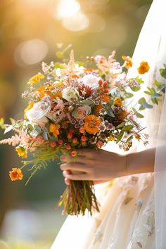 a bride holding a bouquet of flowers in her hand with sunlight shining through the background