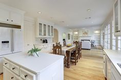 a large kitchen with white cabinets and wood flooring, along with an island in the middle