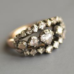 A stunning rare antique Georgian Era (1714-1837) triple row rose cut diamond ring in silver & 10k champagne gold. This beautiful and hard to find triple row rose cut diamond Georgian ring features three separate rows of glittering rose cut diamonds all set in foiled closed back cut down collet sterling silver cups over a gold back, as was typical of the period. The center largest diamond is heart shaped and flanked by diamonds graduating in size with the top and bottom rows bowing outwards i Antique Cluster Ring With Rose Cut Diamonds, Victorian Style Diamond White Rose Cut Diamond Ring, Victorian Rose Cut Diamond Rings, Victorian Rose Cut Diamond Anniversary Ring, Victorian Style Rose Cut Diamond Ring For Anniversary, Victorian Style Ring With Rose Cut Diamonds, Victorian Diamond Ring With Rose Cut Diamonds For Anniversary, Antique Rose Cut Diamond Ring For Anniversary, Antique Silver Cluster Diamond Ring