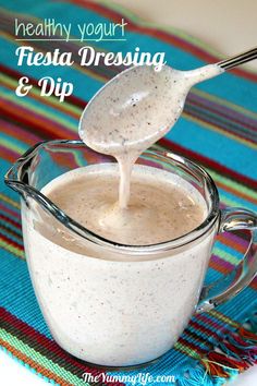 a spoon is being used to dip into a white liquid in a glass mug on a colorful place mat