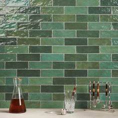 a green tile backsplash in a kitchen with two beakers and three glasses