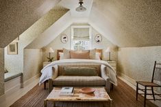 a bed sitting under a window in a bedroom next to a chair and ottoman on top of a hard wood floor