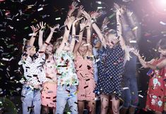 group of children standing in front of confetti and streamers