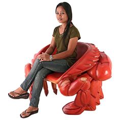 a woman sitting on top of a red crab shaped bench next to a white background