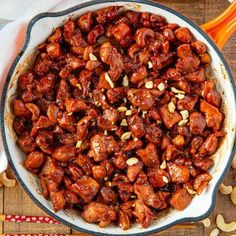 a bowl filled with chicken and cashews on top of a wooden table