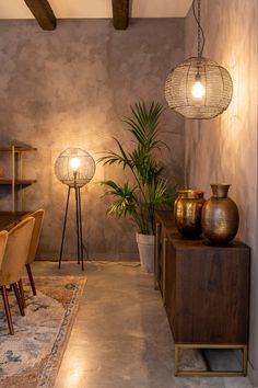 a dining room with two lamps hanging from the ceiling and some plants in vases