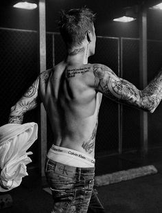 a man with tattoos on his back and arms is standing in front of a mirror