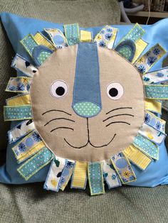 a blue and yellow pillow with a lion face on it's side, sitting on a couch