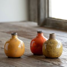 three small vases sitting on top of a wooden table