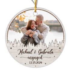 a christmas ornament with an image of two people hugging each other and the words michael & garberia engaged on it