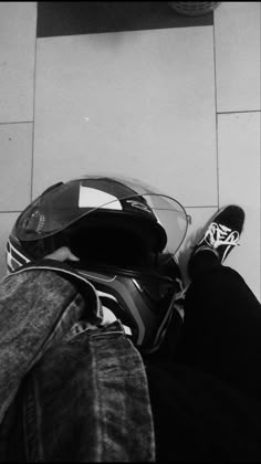 a person with their feet up on the ground wearing a motorcycle helmet and black jeans