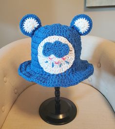 a blue crocheted hat with ears on it sitting on a table next to a chair