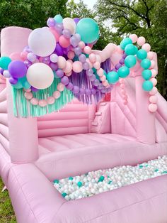 an inflatable bouncer with balloons and streamers on the top is set up for a birthday party