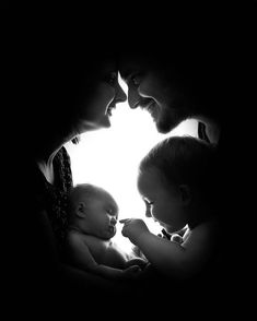 a man and woman holding a baby in their arms while looking at the light from behind them