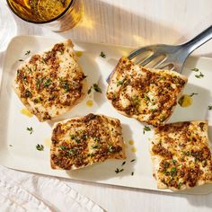 chicken with lemons and capers on a white platter next to a knife