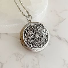 "Now offering custom text engraving.  Visit shop for details. Elevate your style with this stunning and timeless antiqued silver locket. The perfect blend of vintage charm and modern elegance, this piece will complement any outfit, whether dressed up or casual. Crafted from high-quality plated brass, this locket is both lightweight and durable. The 32mm diameter makes it a perfect size for any neckline. The locket opens to reveal a secret place to keep your cherished pictures or messages close to your heart. The locket comes with a stainless steel rolo chain, available in 18\", 20\", 24\" or 30\" length. The hypoallergenic nature of stainless steel makes it an excellent choice for those with sensitive skin. Plus, it will never tarnish or lose its shine, ensuring that this beautiful piece w Vintage Etched Silver Jewelry, Vintage Necklace With Engraving Option For Keepsake, Classic Vintage Charm Locket Necklace, Classic Round Pendant Locket Necklace With Vintage Charm, Antique Silver Etched Necklace As Gift, Vintage White Gold Jewelry With Engraving Option, Classic Locket Necklace With Engraving For Keepsake, Classic Personalized Pendant Locket Necklace, Vintage Silver Personalized Necklaces