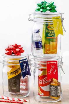 three glass jars filled with different types of drinks and candy canes next to each other