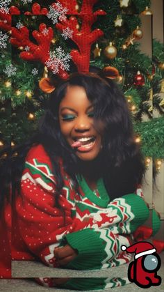 a woman in a red and green christmas sweater sitting next to a christmas tree