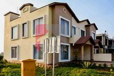 an apartment building with lots of windows and grass in front of the house, on a sunny day