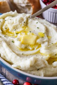 mashed potatoes with butter and herbs in a blue bowl next to cranberries