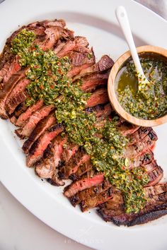 grilled steak with chimica sauce and pesto on it sitting on a white plate