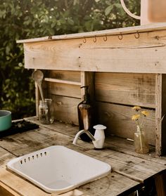 a sink sitting on top of a wooden table next to a potted yellow flower