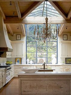 a kitchen with an island in the middle of it and a chandelier hanging from the ceiling