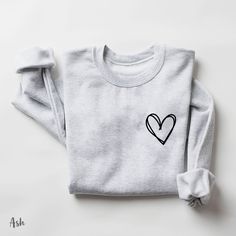 "Heart sweatshirt, Pocket Heart Hoodie, Heart Sweatshirt, Heart Outline Hoodie, Cute Hoodie, Cute Sweatshirt, gifts for her, sweatshirt gift How to Order 1* View all color and size charts before you place your order. 2* Select your shirt \"SIZE\" and \"COLOR\". 3* Click add to cart.  If you are ordering more than 1 item, you need to repeat this process for each item you wish to order. Product Information Gildan Hoodie- Sweatshirt 8 oz.(US) 13.3 oz.(CA), 50/50 preshrunk cotton/polyester Heather S Crop Crewneck, Club Sweatshirts, Heart Sweatshirt, Mama Sweatshirt, Emergency Room, Sports Sweatshirts, Sweater Gift, Knit Sweatshirt, Casual Sweatshirt