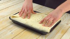 a person that is making some kind of tortilla on a wooden counter top