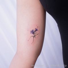 a small purple flower tattoo on the arm