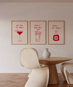 three framed art prints hang on the wall above a round table with two chairs and a vase