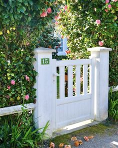 a white gate surrounded by pink roses and greenery with the number fifteen on it