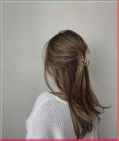 a woman with her hair in a ponytail wearing a white sweater and pink frame around her neck