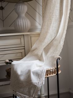 a white blanket sitting on top of a chair next to a window