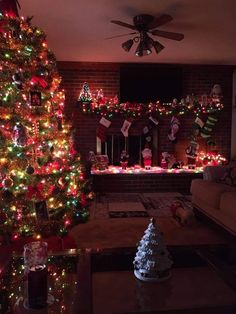 a living room decorated for christmas with lights on the tree and decorations around the fireplace