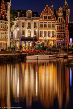 the city is lit up at night with lights reflecting in the water and buildings on both sides