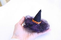 a hand holding a small purple witch hat