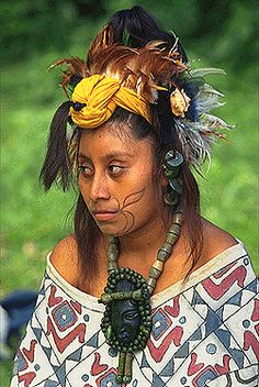 a woman wearing an elaborate headdress and feathers on her head is looking at the camera