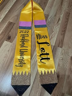 two yellow and purple graduation sashes on the floor