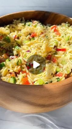 a wooden bowl filled with rice and vegetables on top of a white tableclothed surface