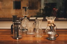 several different types of coffee makers on a wooden table