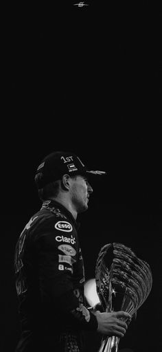 a black and white photo of a man holding a baseball glove in front of a dark background