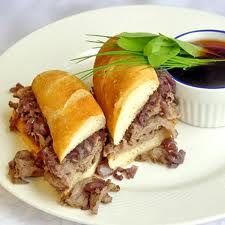 a sandwich cut in half sitting on top of a white plate next to a dipping sauce