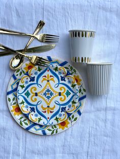 a colorful plate and silverware on a white table cloth with a cup in the background