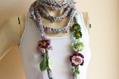 a woman wearing a white tank top and multicolored crocheted flower necklace