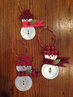 three snowmen made out of buttons sitting on top of a wooden table