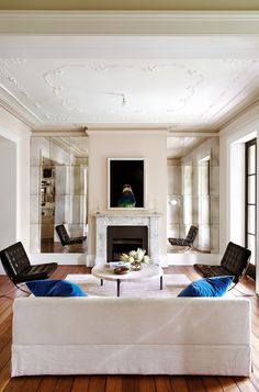 a living room filled with furniture and a fire place in front of a mirror wall