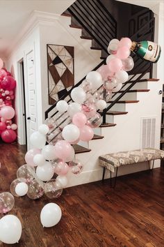 balloons are floating down the stairs in front of a staircase decorated with pink and white balloons