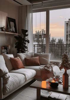 a living room filled with furniture and a large window overlooking the cityscape at sunset