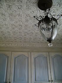 a chandelier hanging from the ceiling in a room with white walls and blue doors